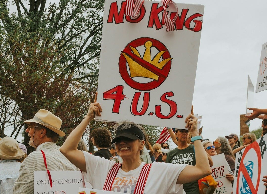 Protesters hold signs that say "no king for us" Protesters hold signs that say "no king for us"