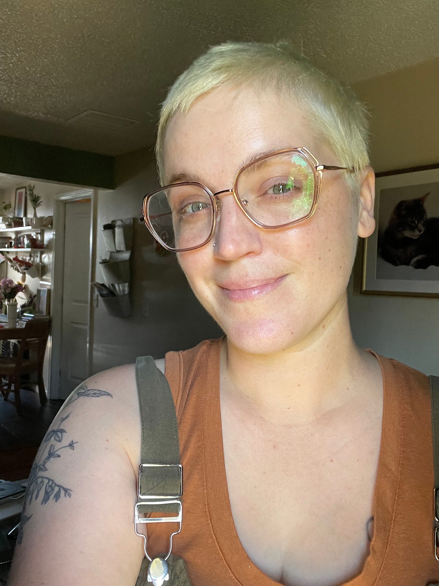 a white person with short bleached blonde hair is smiling at the camera