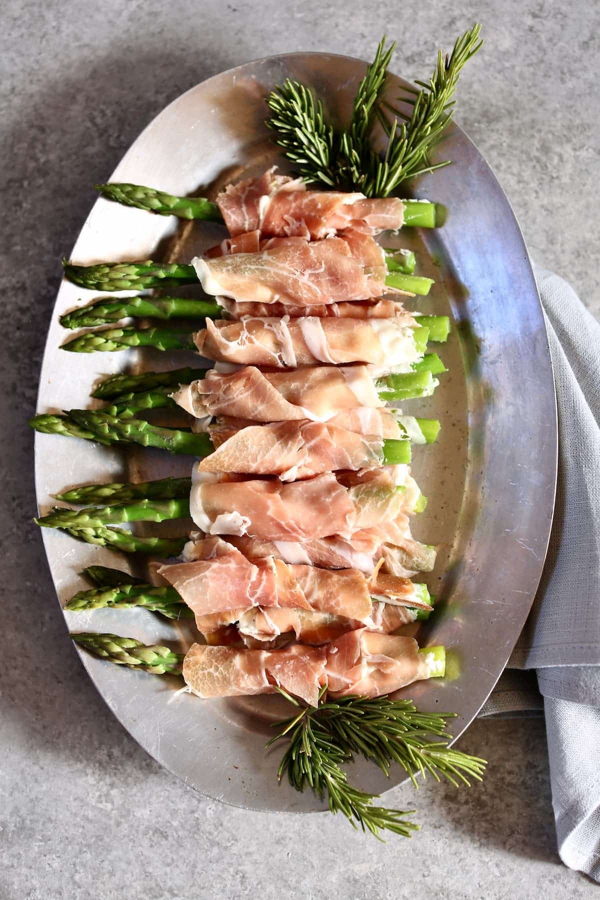 a photo of asparagus and prosciutto appetizers on a silver platter.