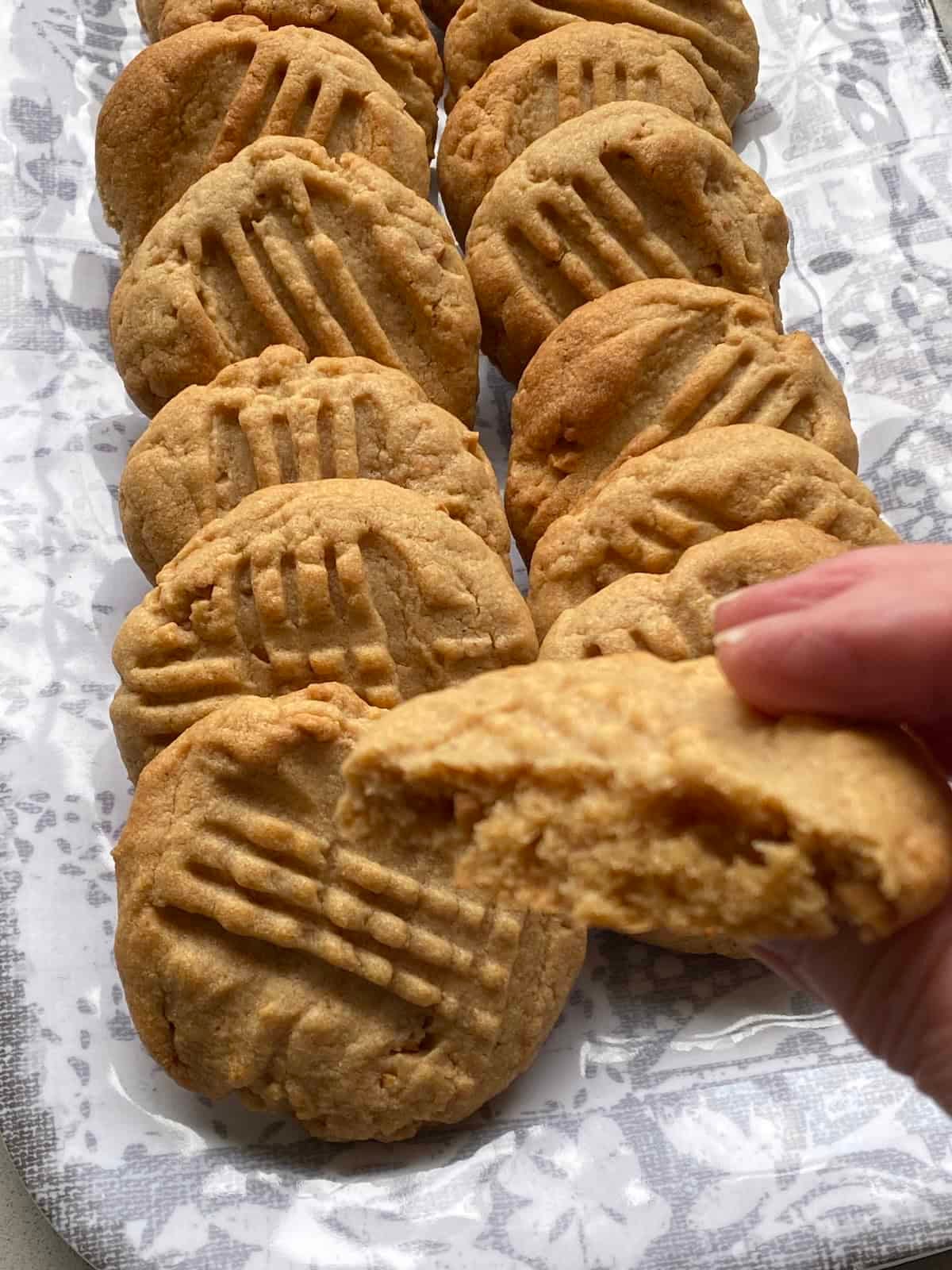Chunky Peanut Butter Cookies on a tray, with one being held. Chunky Peanut Butter Cookies on a tray, with one being held.