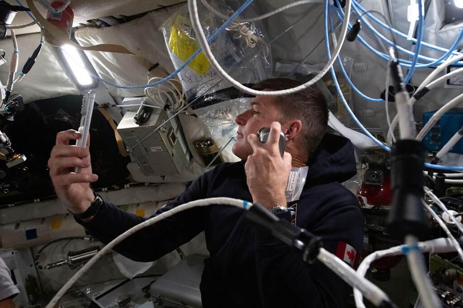 An astronaut in a capsule shaving while surrounded by tubing. An astronaut in a capsule shaving while surrounded by tubing.