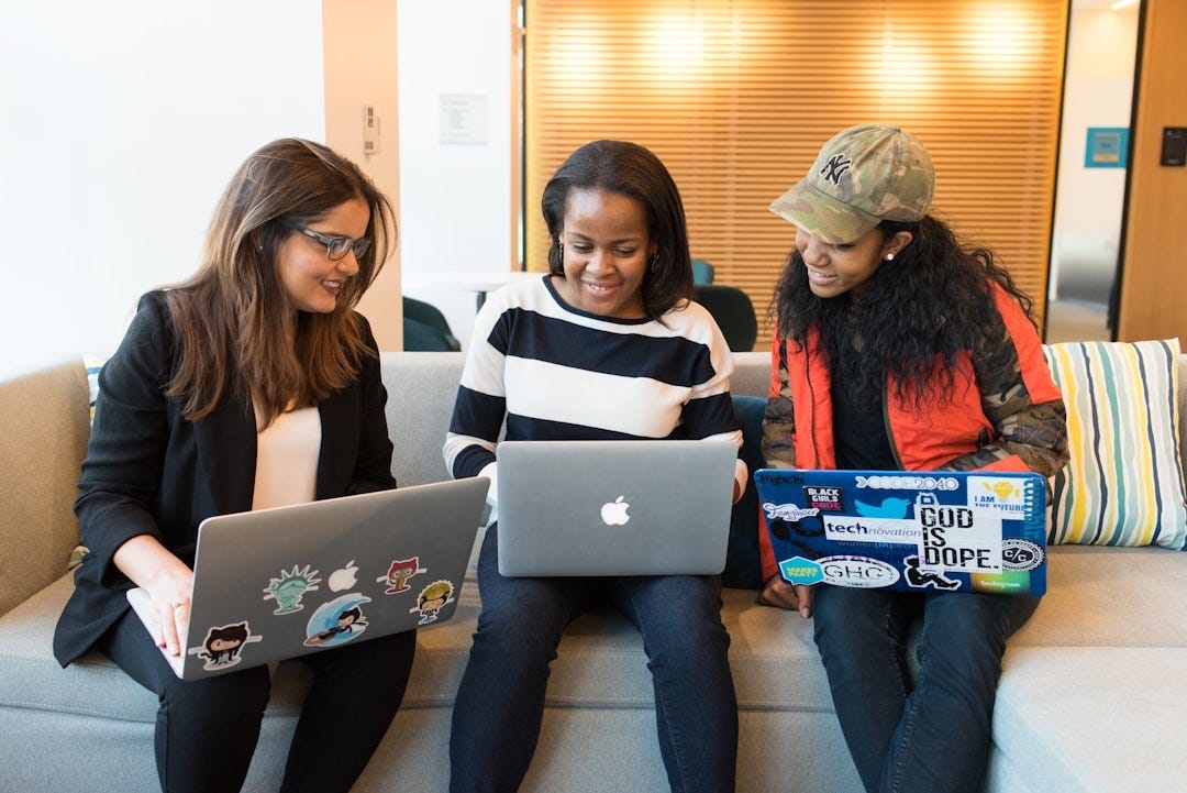 three women sitting on sofa with MacBook three women sitting on sofa with MacBook