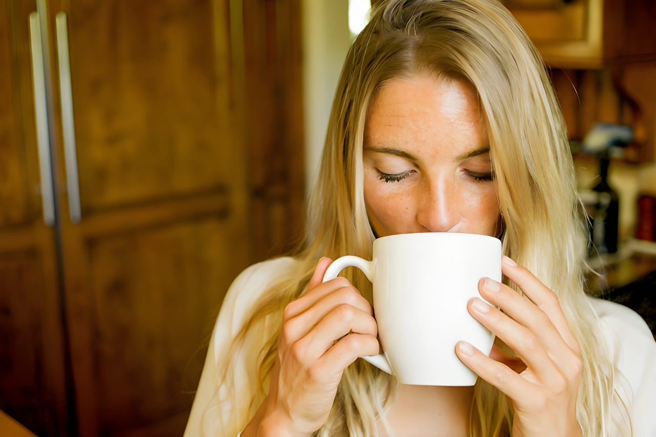 Woman sipping a beverage out of a white mug Woman sipping a beverage out of a white mug