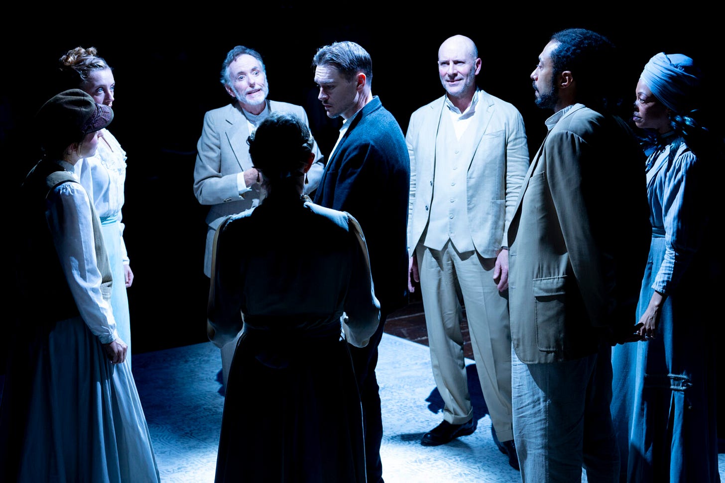 A man with a sad face stands in the middle of a circle of other people in a stark white light A man with a sad face stands in the middle of a circle of other people in a stark white light