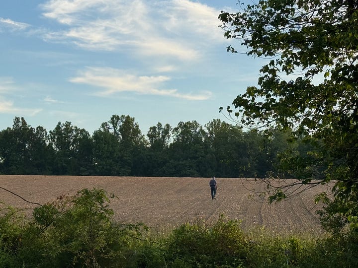An old man with a cane in a dry field