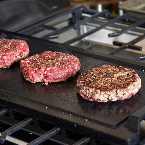 burgers on a grill, burger patty topped with cheese, assembled burger