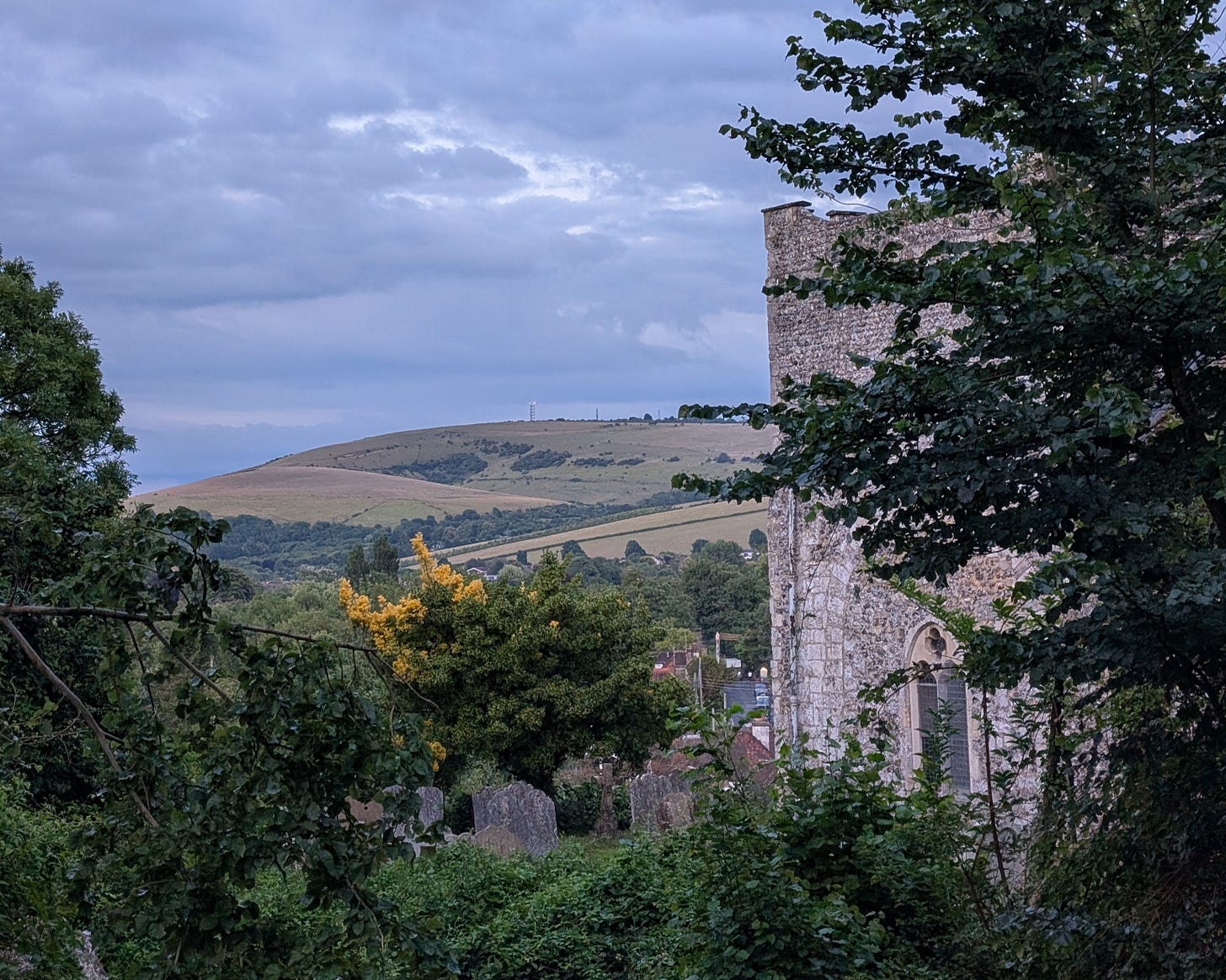 A view of the South Downs in Sussex England, featuring rolling hills and a stone church