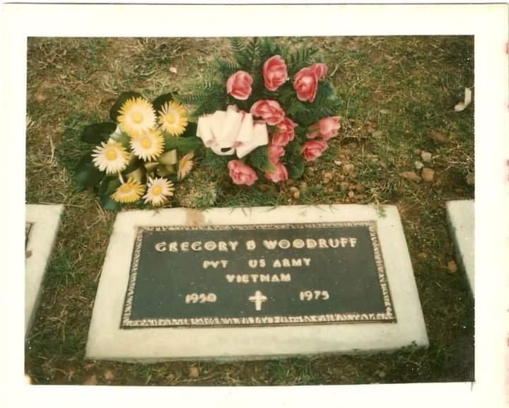 A vintage photo of Michele's father's gravestone with yellow and red silk flowers above it.   