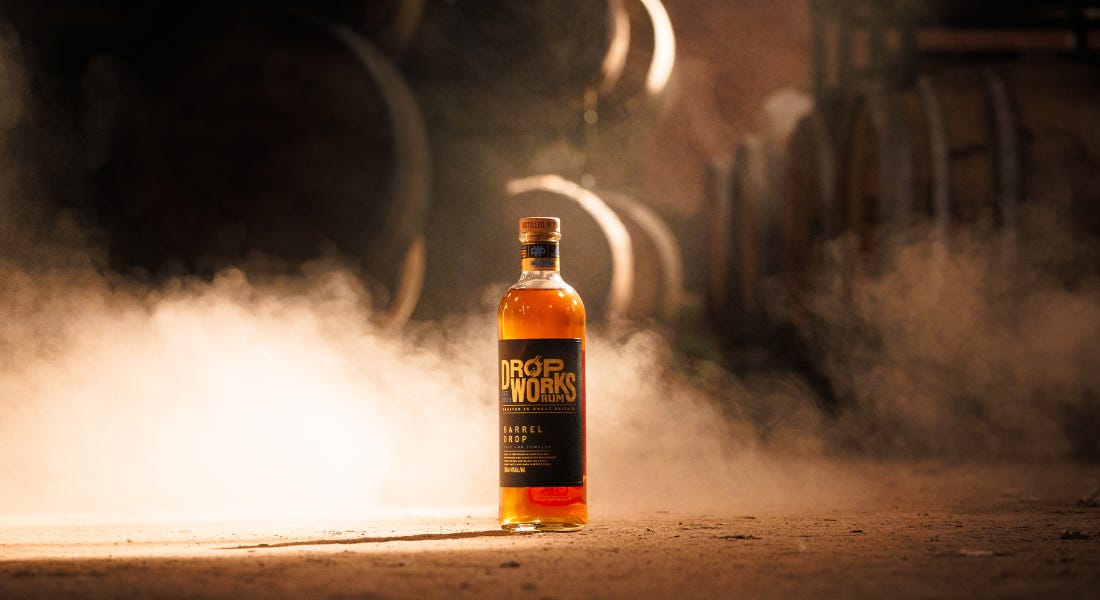 A glass bottle of rum on the floor, with steam around it and barrels behind it A glass bottle of rum on the floor, with steam around it and barrels behind it