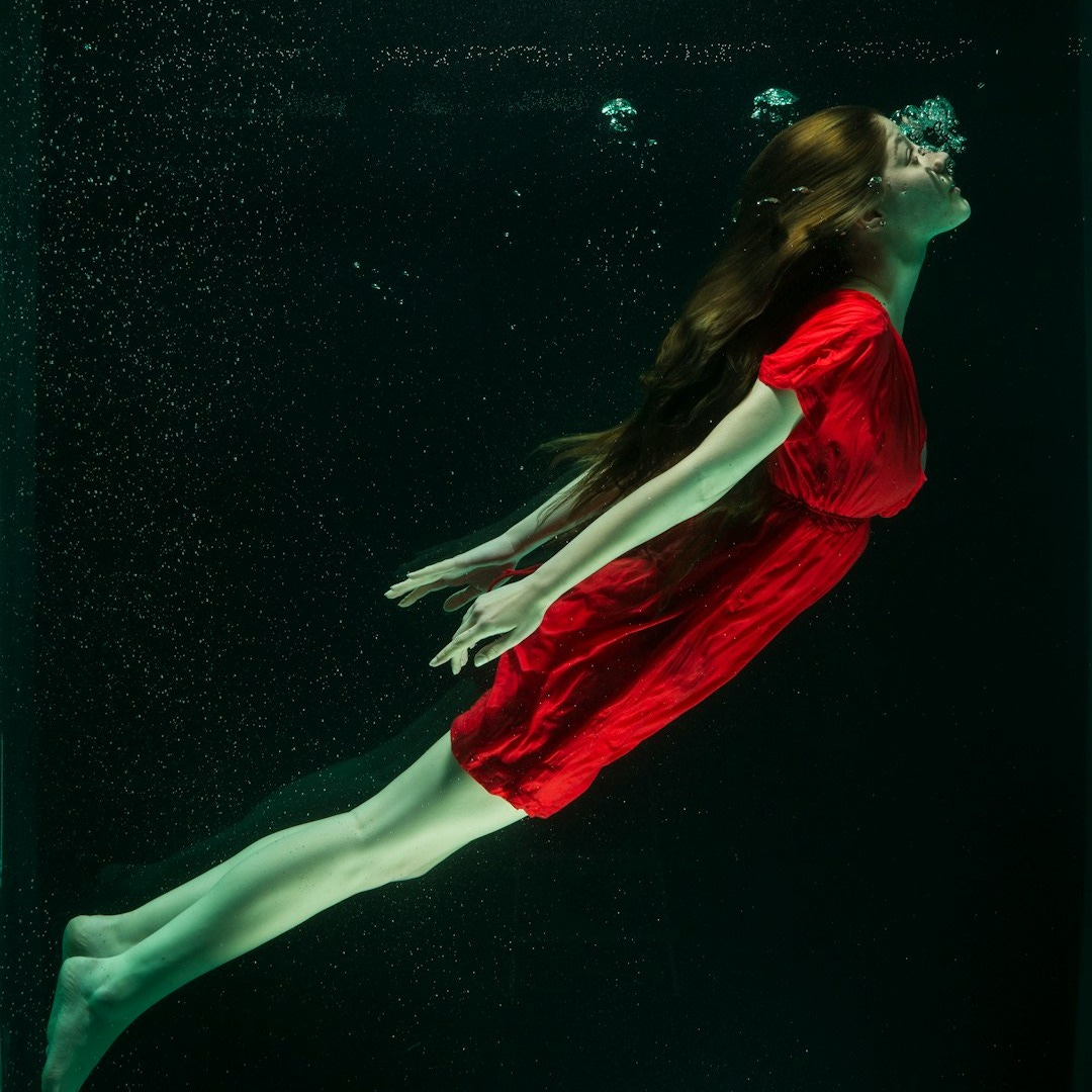 woman in red dress lying on water