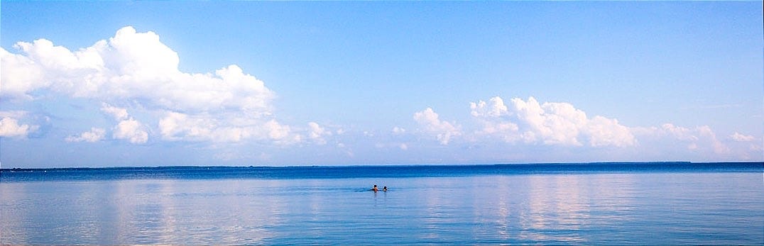 body of water under blue and white sky at daytime