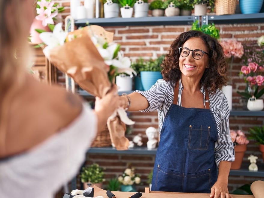 Middle-aged woman working as a florist hands a bouquet to a customer. Middle-aged woman working as a florist hands a bouquet to a customer.