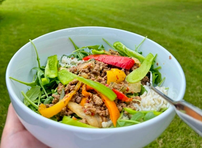 firecracker beef bowl in a white bowl outside in a green area firecracker beef bowl in a white bowl outside in a green area