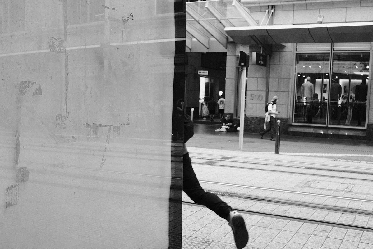 A person walking by only half visible on a city street- black and white photo