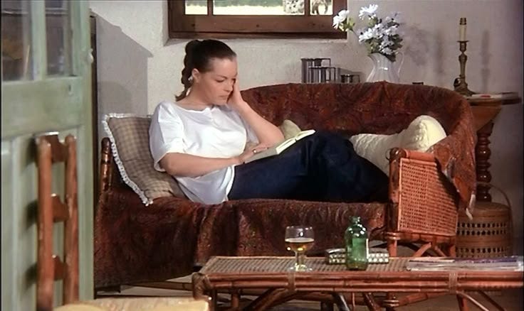 This may contain: a woman sitting on a couch reading a book This may contain: a woman sitting on a couch reading a book