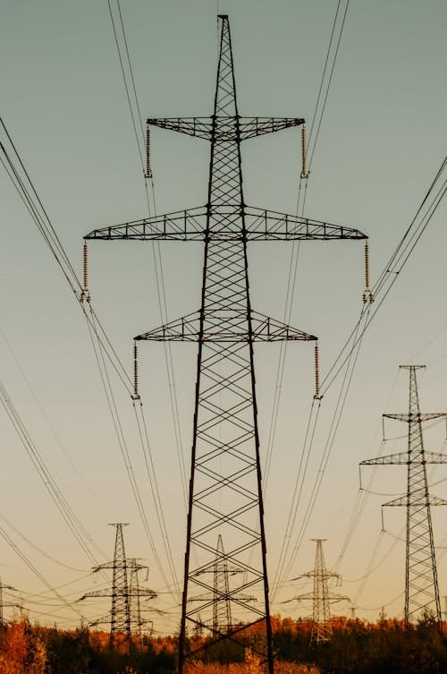 Free A scenic view of high voltage power lines against a serene sunset sky. Stock Photo
