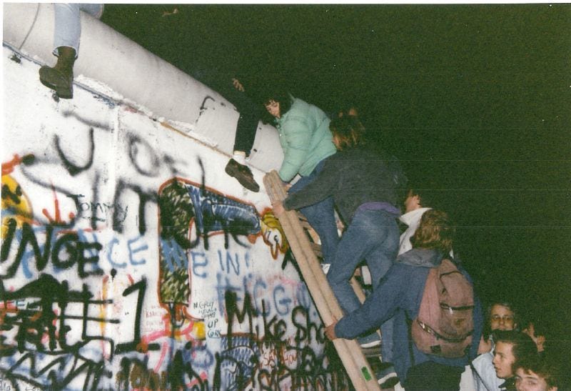 People climbing over the Berlin Wall