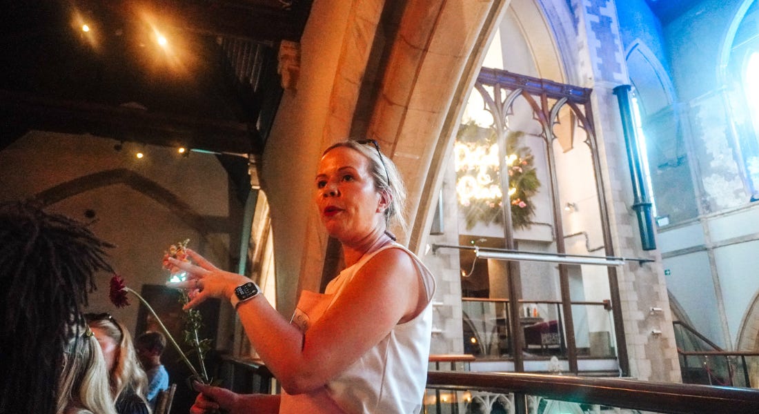 A woman with blonde hair with a white vest talking, inside a church A woman with blonde hair with a white vest talking, inside a church