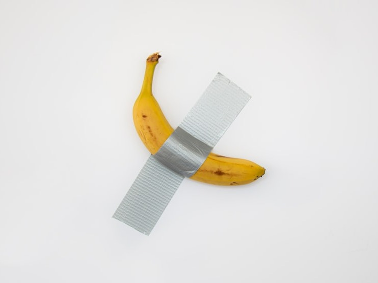 taped yellow banana on white surface taped yellow banana on white surface