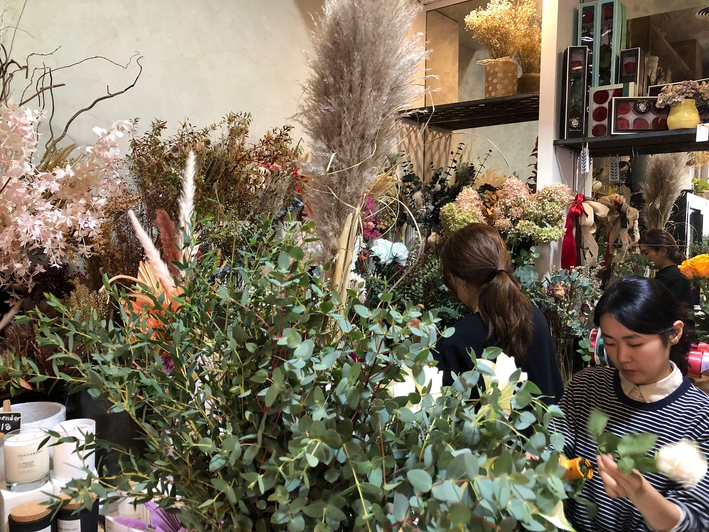 two people working behind a counter at a florists shop