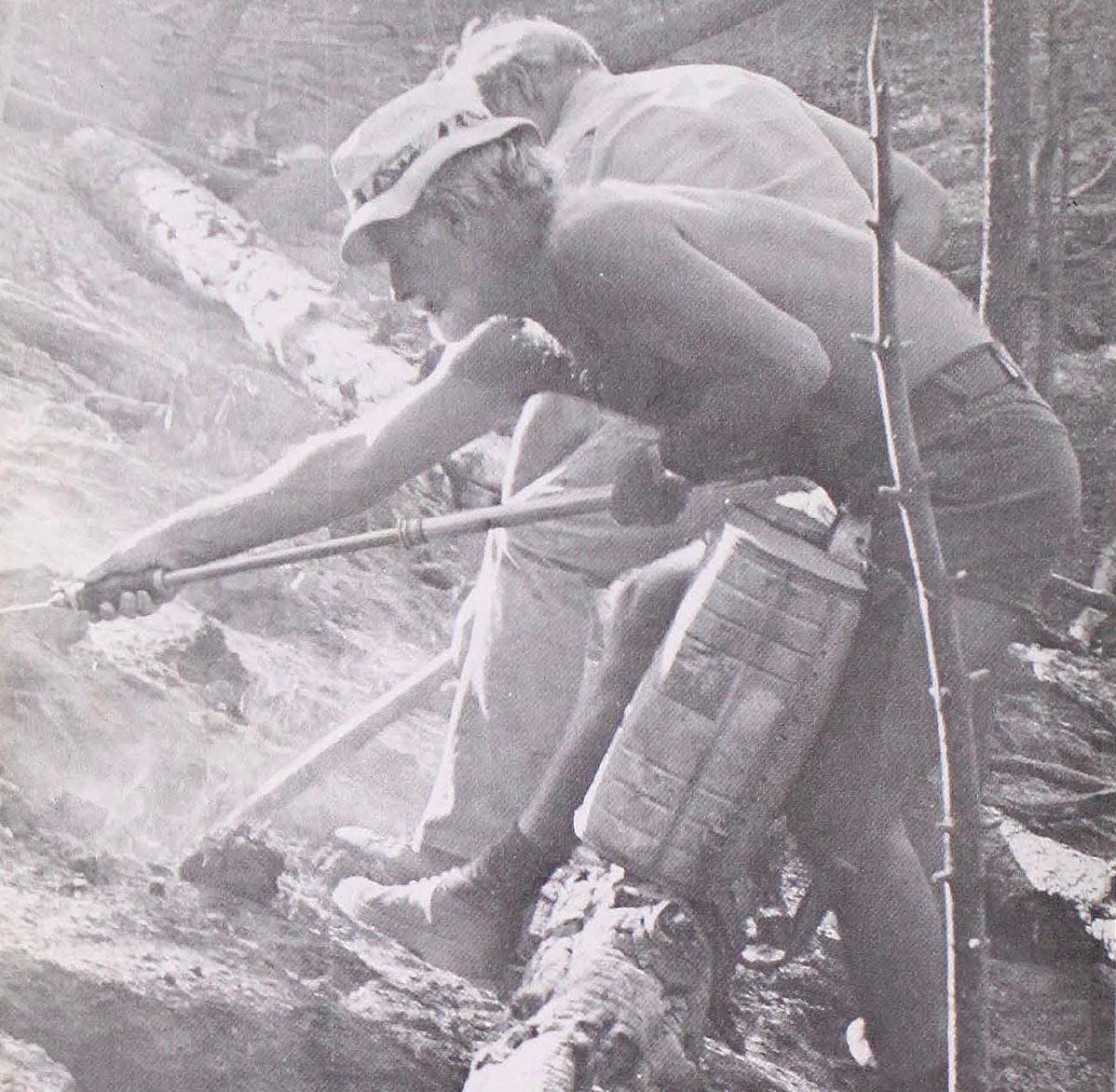 Two men on a smoky hillside use backpack sprayers and hand tools to combat a wildfire threatening Mountain Air Ranch in 1978.