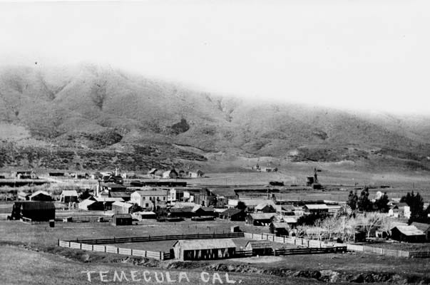 Black and white photograph of the small town of Temecula, California, in 1909, showing a few dozen wooden buildings with mountains rising behind them. Black and white photograph of the small town of Temecula, California, in 1909, showing a few dozen wooden buildings with mountains rising behind them.