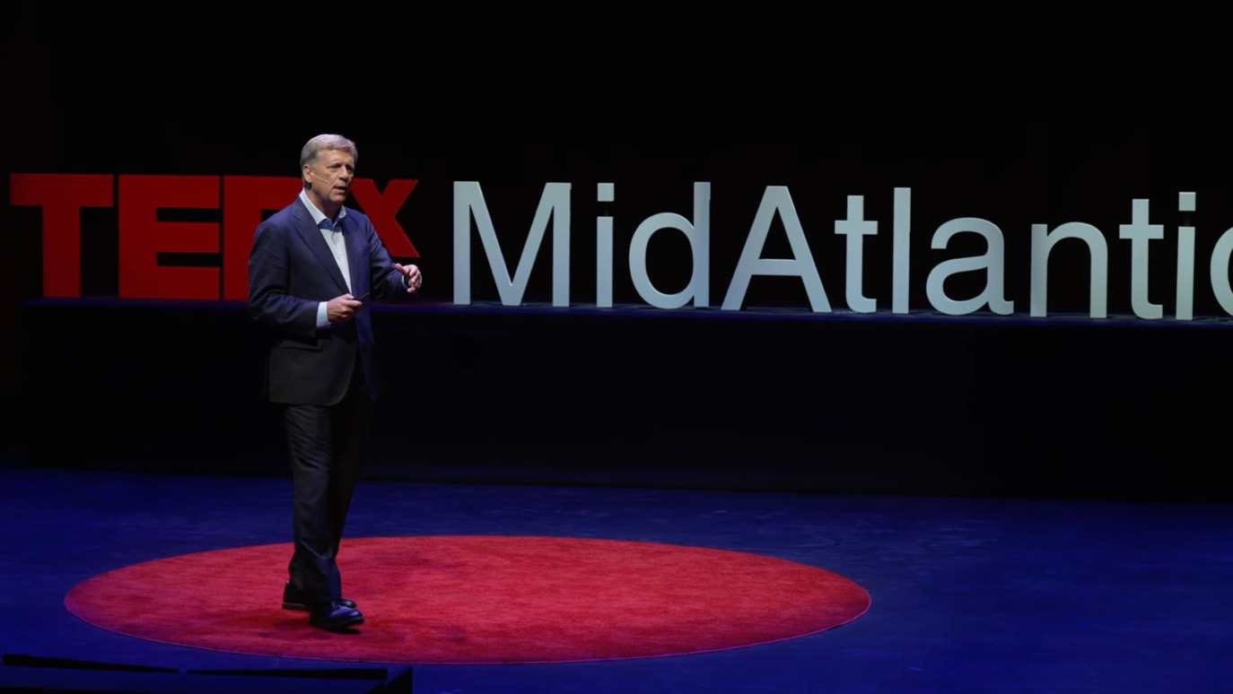 A person in a suit on a stage

AI-generated content may be incorrect.