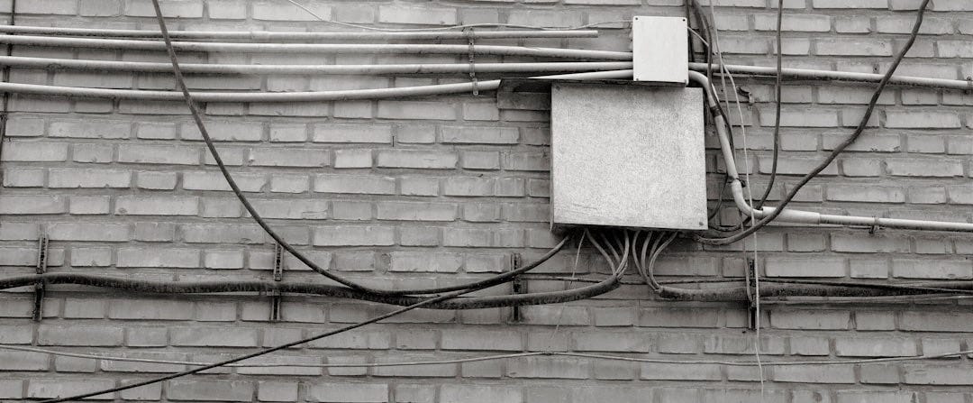 a black and white photo of an electrical box on a brick wall