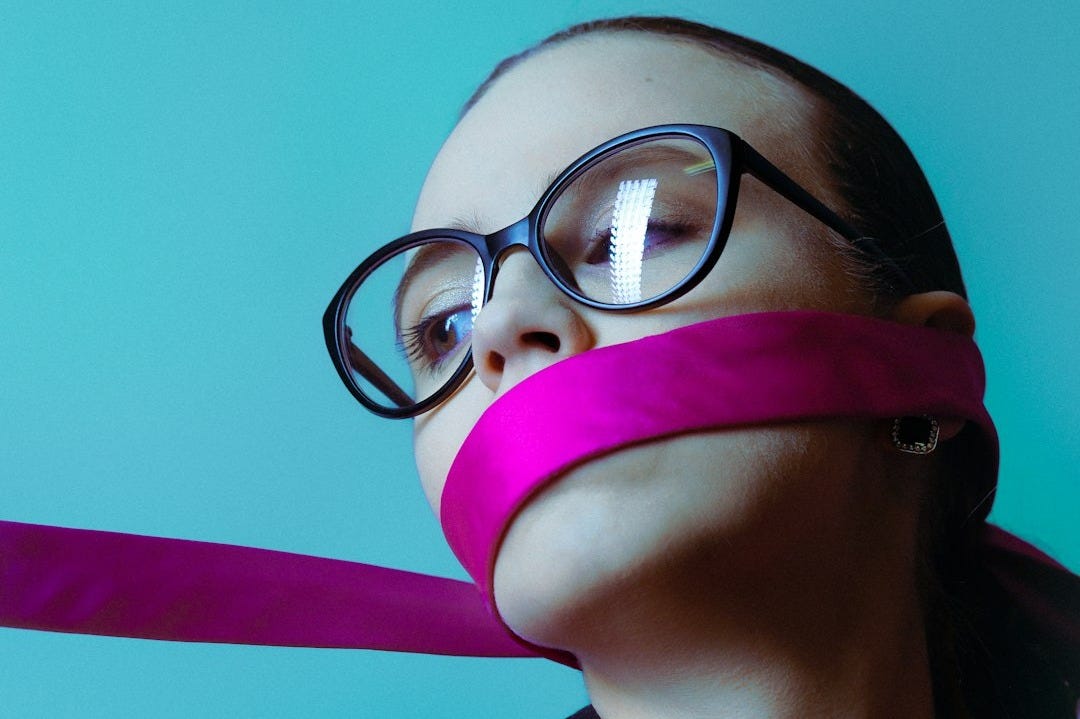 Woman with pink ribbon over mouth and glasses