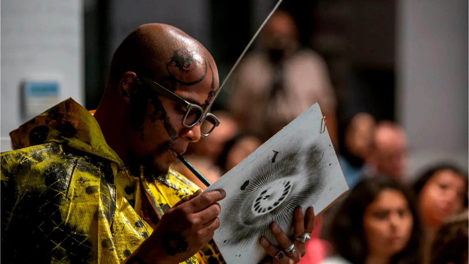 Brazilian artist Dig Ferreira painting with a Japanese sumi brush held in his mouth at a live event