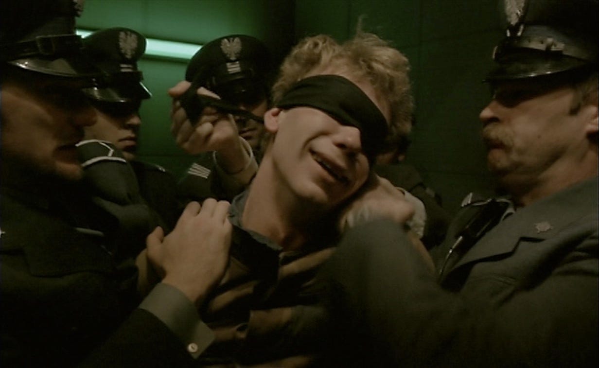 A blindfolded man crying while surrounded by Polish troops.