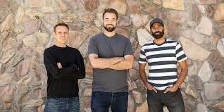 Substack founders Hamish McKenzie, Chris Best, and Jairaj Sethi pose for a photo in front of a brick wall.