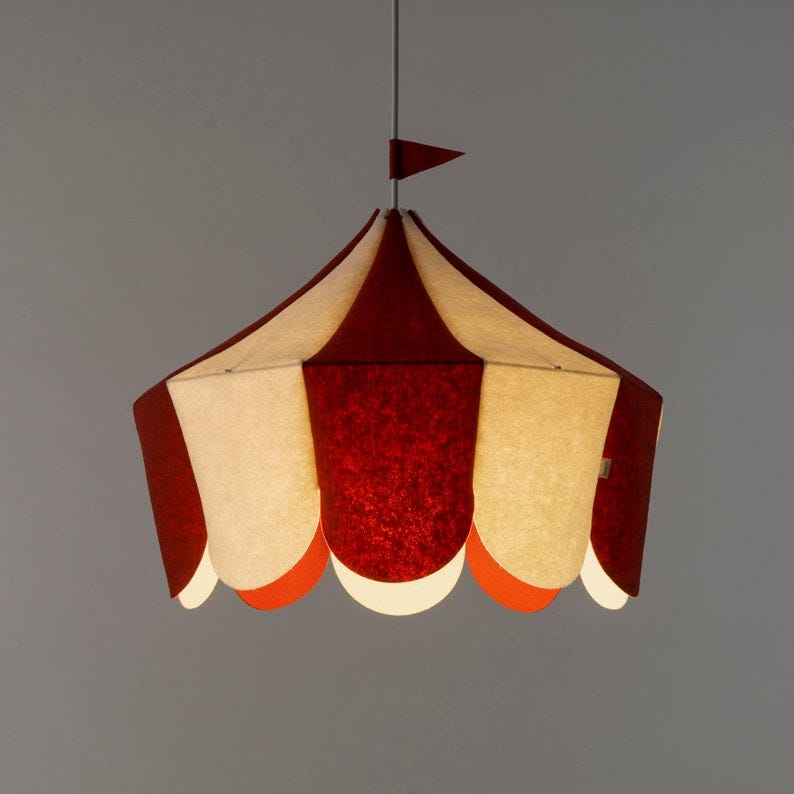 May include: A red and white circus tent-shaped pendant light fixture with a small red flag on top. May include: A red and white circus tent-shaped pendant light fixture with a small red flag on top.