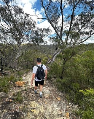 guy with a backpack on a hike, surrounded by trees