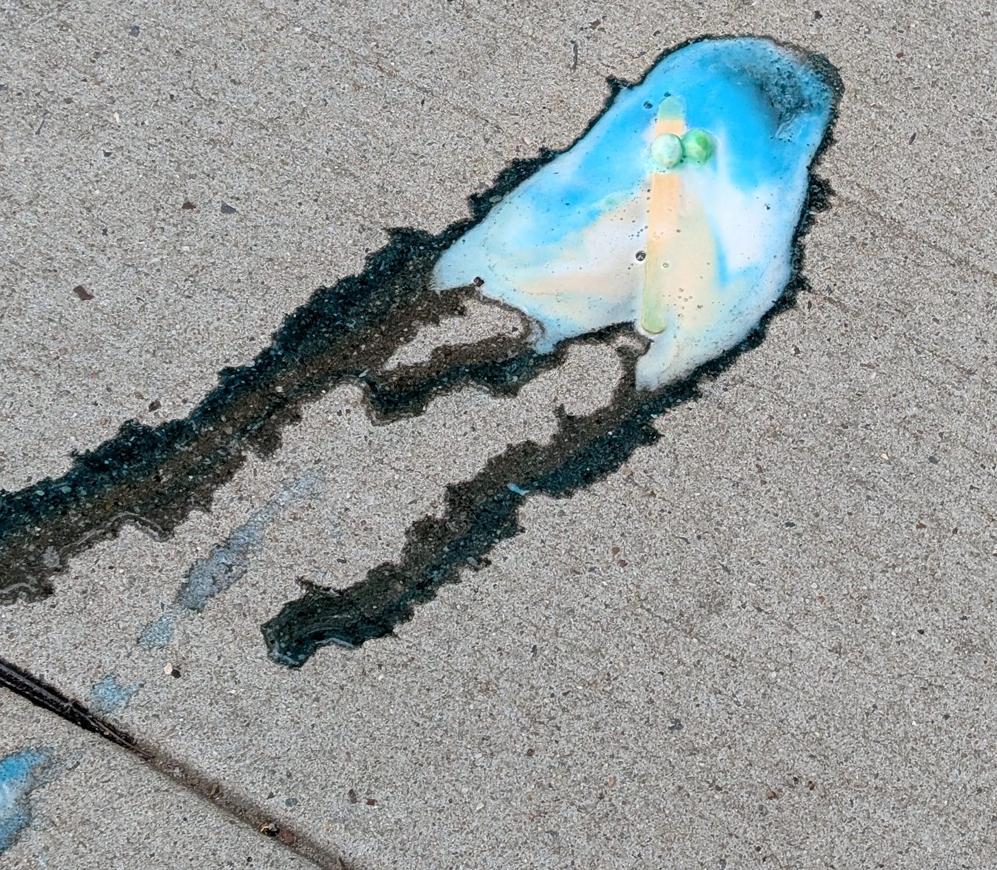Image of a melted popsicle on a gray concrete sidewalk. The two candy eyes and popsicle stick are visible in the puddle Image of a melted popsicle on a gray concrete sidewalk. The two candy eyes and popsicle stick are visible in the puddle