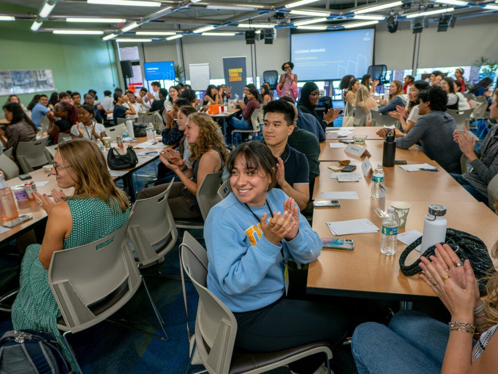 students sit in rows of long tables in a classroom students sit in rows of long tables in a classroom