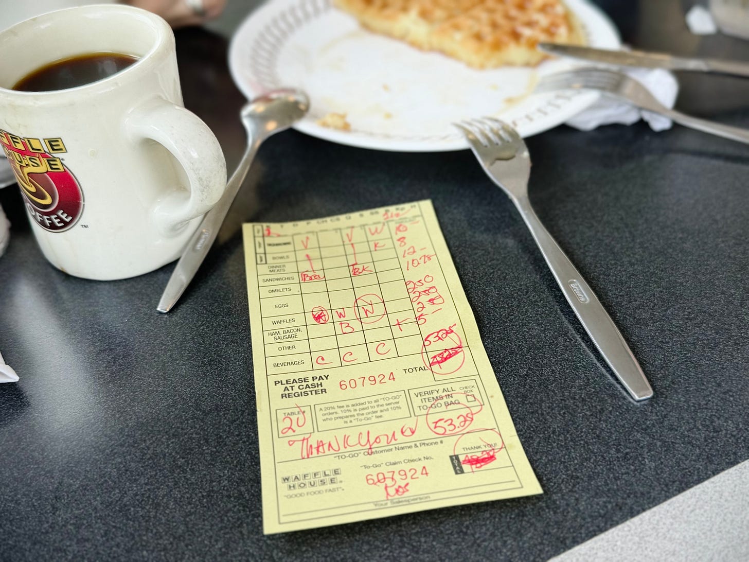 Addition manuscrite Waffle House sur papier jaune, à côté d’une tasse de café et d’une assiette de gaufre terminée. Addition manuscrite Waffle House sur papier jaune, à côté d’une tasse de café et d’une assiette de gaufre terminée.