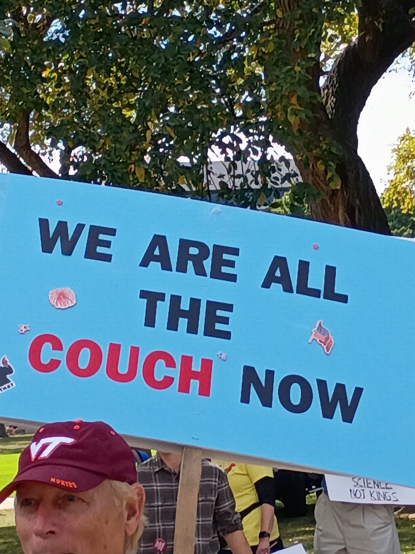 Protest sign reading “We are all the couch now."