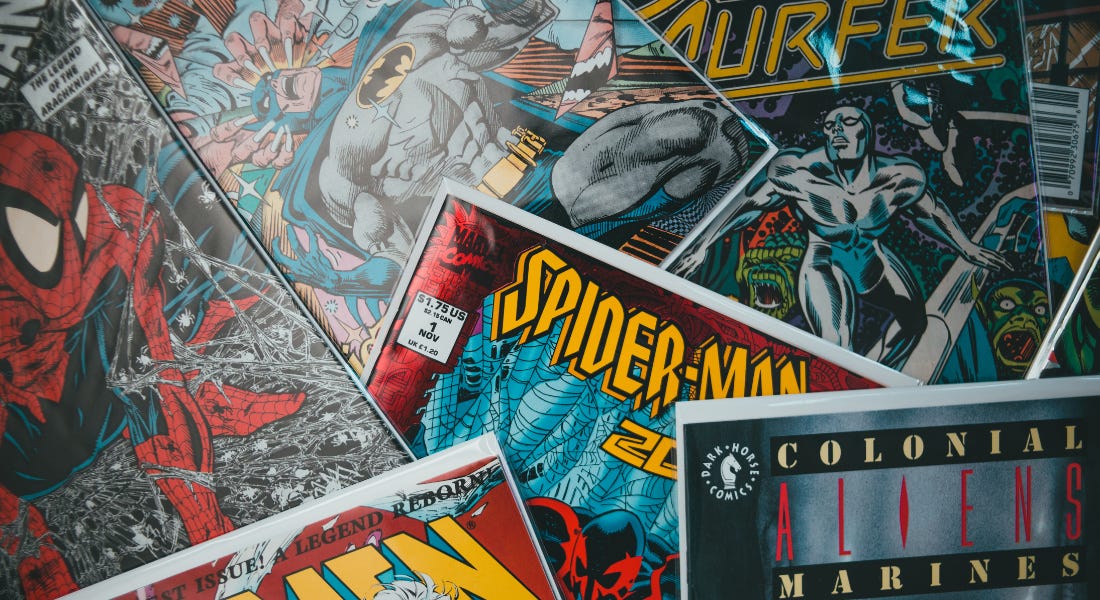A flat lay of white, blue, yellow, and red comic books with Spiderman and Batman on them