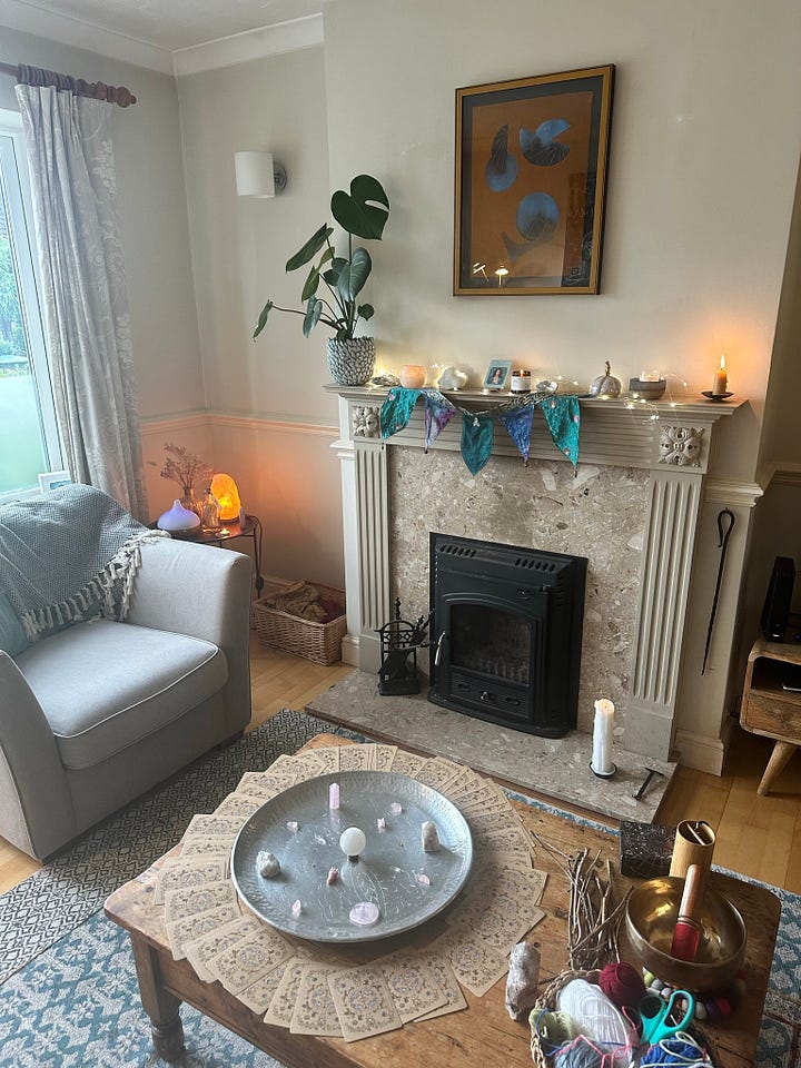 A fireplace decorated with flags and a plant showing candles and fairy light. A silver dishing holding a crystal grid surrounded by oracle cards.