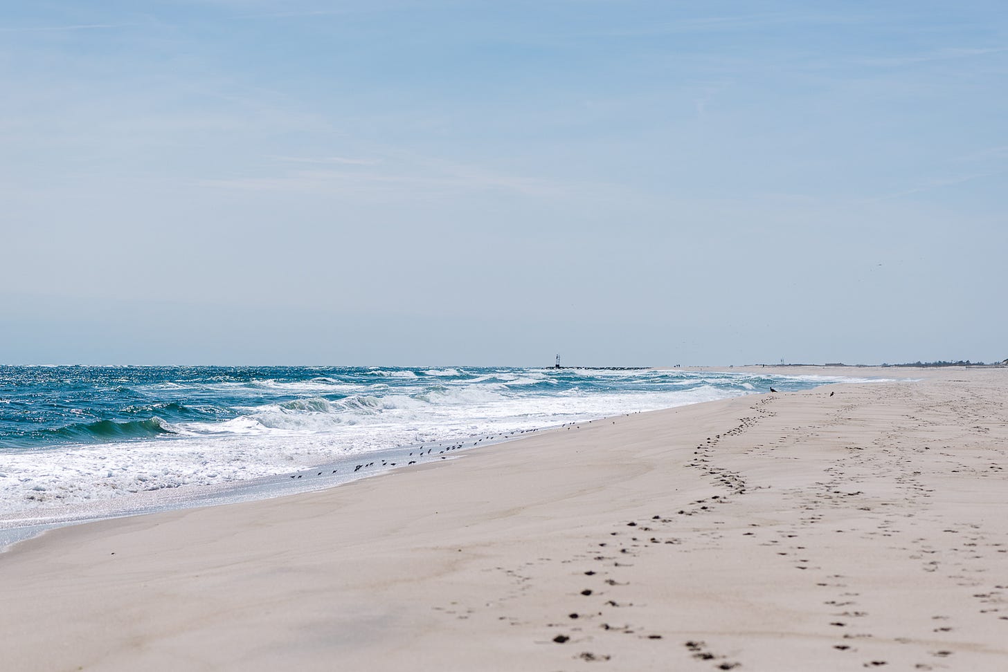 Waves on a beach with footprints in the sand.