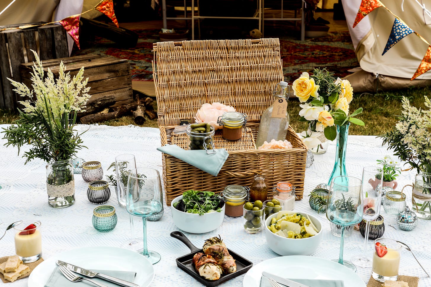 picnic basket and food on white blanket outside