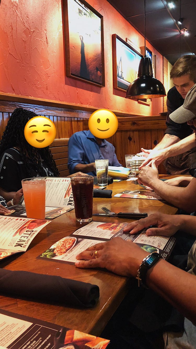 Family around a table at a restaurant with emoji faces to censor