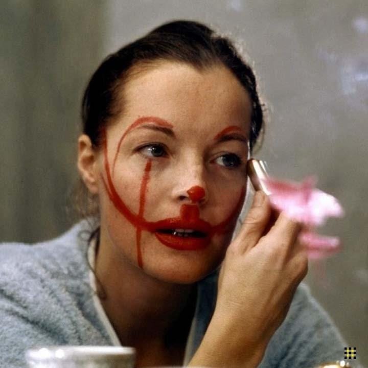 This may contain: a woman with makeup painted on her face is looking at the mirror and applying lipstick