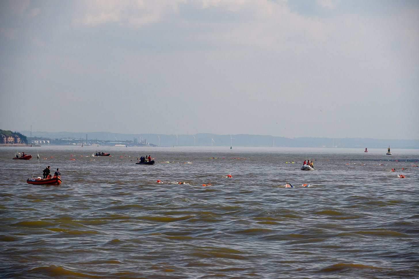 Orange dots in the water are toe floats from swimmers. There are hills way off in the distance.