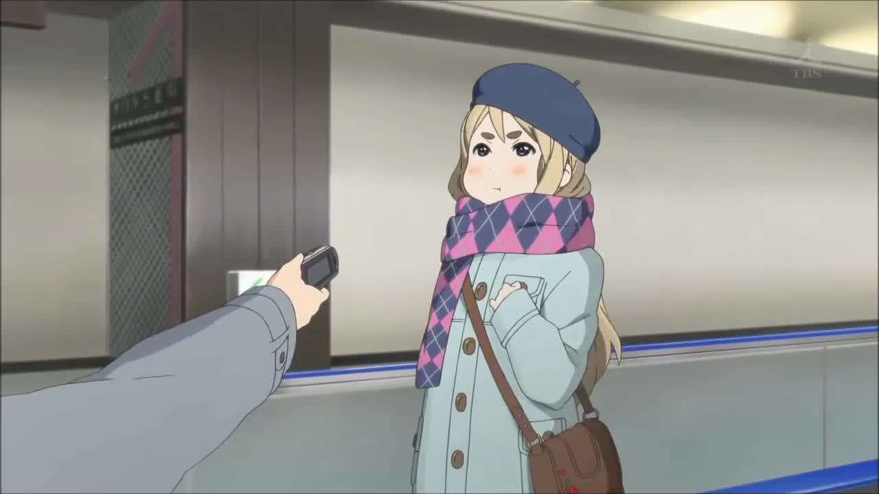 Tsumugi Kotobuki, unamused, in Narita airport, being accosted by somebody holding a camera.