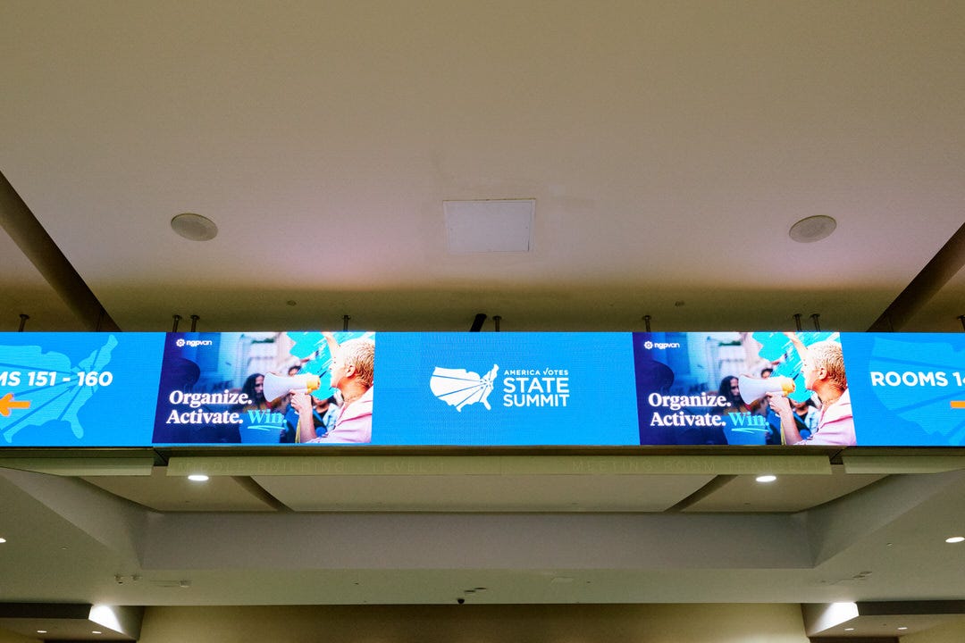 Digital signage banner in the Walter E Washington Convention Center hallway reading Organize Activate Win with the America Votes State Summit logo