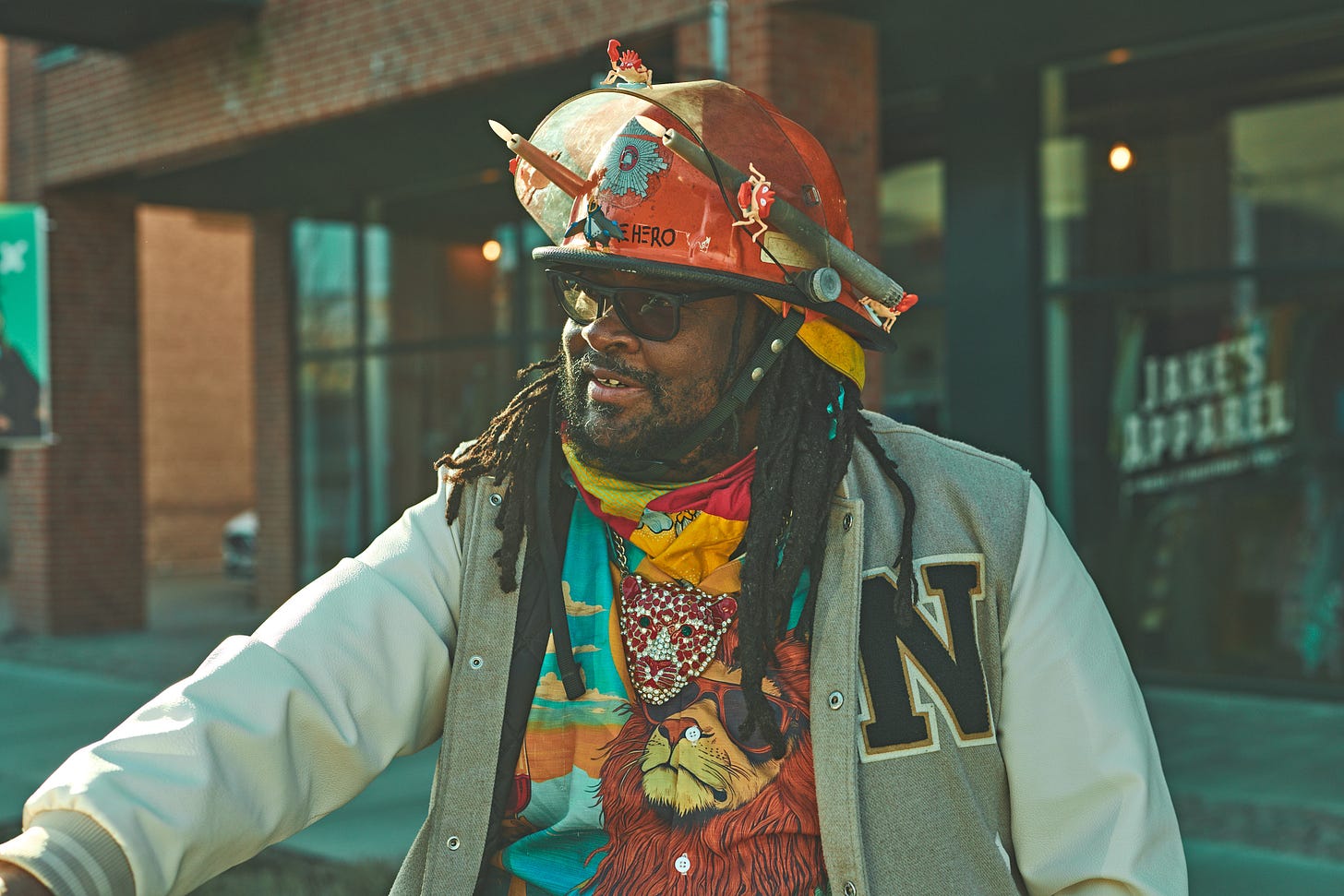 FatbikeHero in Fireman Helmet Performance Art Costume in Front of Jake’s Apparel Store in Aarhus C. Fireman helmet has crab toys attached at two artificial candle lights