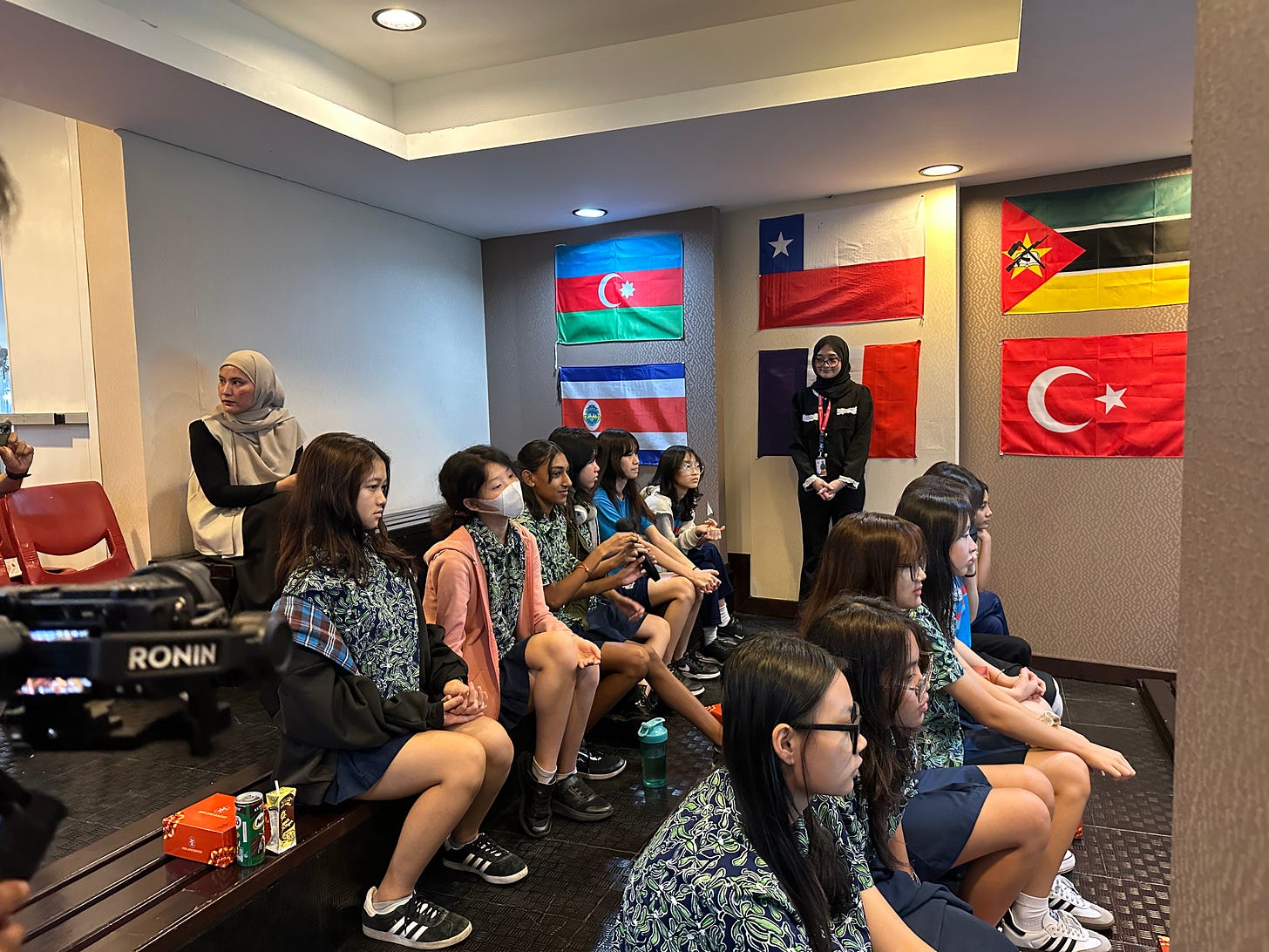 students sitting on a hall with national flags on the wall attending a discussion about affordable international education students sitting on a hall with national flags on the wall attending a discussion about affordable international education