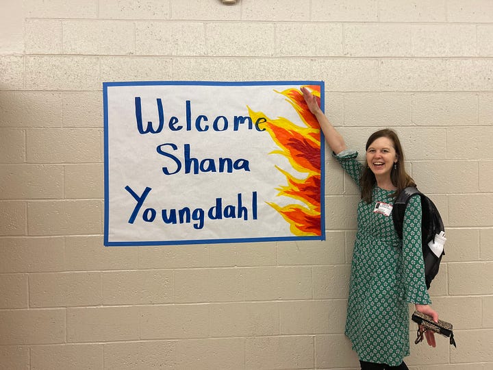 Shana Youngdahl with a sign that says "Welcome Shana Youngdahl" painted with flames, tiny gnomes ontop of the book A Catalog of Burnt Objects by Shana Youngdahl, Shana Youngdahl with a cart of books to sign for students, Shana Youngdahl with the library and a teacher from Centennial High